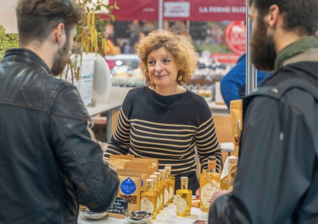 Exposante souriante discussant avec des visiteurs
